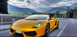 Un elegante automóvil amarillo de "Conduce un Ferrari o Lamborghini en Córdoba" recorre una pintoresca carretera de montaña, con como telón de fondo unas verdes colinas y un espectacular cielo nublado. - ForTwo - Planes para parejas