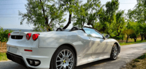 Un elegante convertible blanco de la experiencia "Conduce un Ferrari o Lamborghini en Córdoba" se encuentra en una carretera pintoresca, envuelto de exuberantes árboles verdes bajo los cielos despejados de Córdoba. - ForTwo - Planes para parejas
