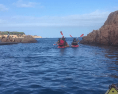 Dos kayakistas navegan entre acantilados rocosos cerca de Girona en una aventura de Escape Room en Kayak, rodeados de un mar que promete emoción bajo el inmenso cielo azul. - ForTwo - Planes para parejas