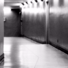 Un pasillo estrecho y poco iluminado, con paredes lisas y reflejos angulares, crea un ambiente inquietante que recuerda a "Escape room ciberataque en Bilbao". - ForTwo - Planes para parejas