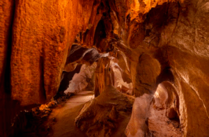 Descubra el interior rocoso e iluminado de la cueva de la Excursión a las Cuevas de San José, donde imponentes formaciones de color marrón rojizo crean caminos sinuosos para una emocionante aventura, revelando el fascinante encanto de esta joya escondida. - ForTwo - Planes para parejas