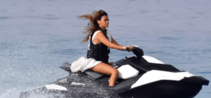 Una persona a bordo de un Explora el Mediterráneo en moto de agua recorre el Mediterráneo a toda velocidad, en blanco y negro, con un chaleco salvavidas, dispuesta a explorar el vasto horizonte. - ForTwo - Planes para parejas