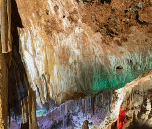 El interior exquisitamente iluminado de Explora las Cuevas de Génova es una maravilla para la vista, con estalactitas colgando elegantemente del techo, invitando a los turistas a un viaje inolvidable. - ForTwo - Planes para parejas