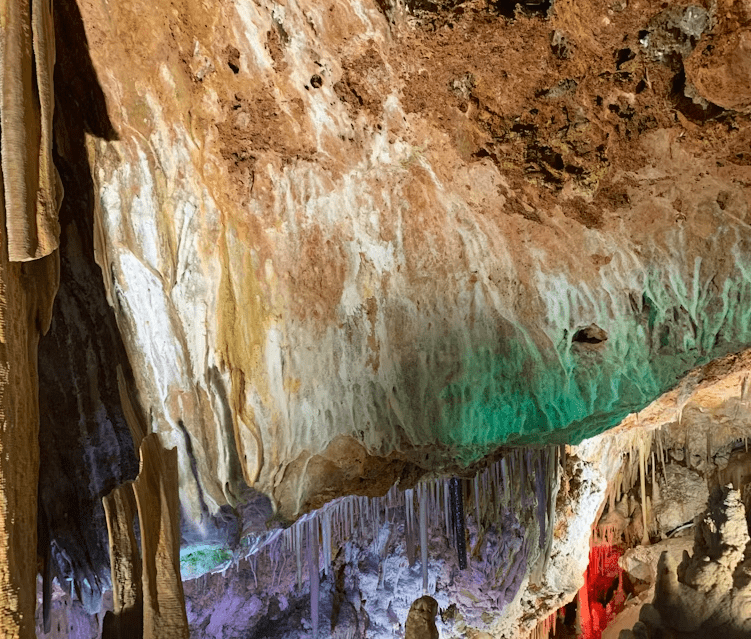 El interior exquisitamente iluminado de Explora las Cuevas de Génova es una maravilla para la vista, con estalactitas colgando elegantemente del techo, invitando a los turistas a un viaje inolvidable. - ForTwo - Planes para parejas