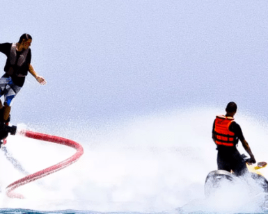 Sobre las cristalinas aguas de Alcocéber, una persona desafía con gracia la gravedad en un Flyboard en Alcocéber mientras recibe la guía experta de otra en una moto acuática. - ForTwo - Planes para parejas