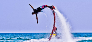 En el vibrante paraíso costero de Alcocéber, un individuo atrevido utiliza un Flyboard en Alcocéber para realizar una acrobacia emocionante, elevándose sobre el océano y dejando un rastro de agua pulverizada contra el cielo despejado. - ForTwo - Planes para parejas