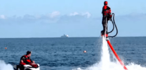 Sobrevolando el resplandeciente mar de Valencia en un flyboard, una persona se mueve con gracia por el cielo como un maestro. Abajo, otro aventurero admira el espectáculo aéreo desde su moto acuática, cautivado por el espectáculo. - ForTwo - Planes para parejas