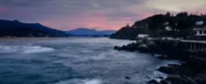 Experimente la vista costera al atardecer con un cielo rosado en Bilbao, donde las suaves olas acarician la costa rocosa y las casas se encaraman en una ladera, a través de nuestra iniciación a la vela "Iniciación a la vela en Bilbao". - ForTwo - Planes para parejas