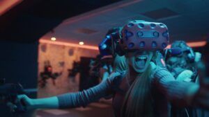 En una habitación poco iluminada, alguien explora con entusiasmo Láser Tag VR: Defiende Valencia de una invasión alienígena con un casco VR, completamente inmerso en este electrizante escenario. - ForTwo - Planes para parejas
