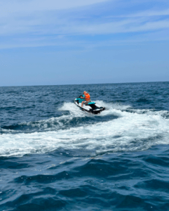 Dos personas viajan en la Moto de agua en Getxo sin carnet en el océano, creando olas blancas bajo un cielo azul claro frente a la costa de Getxo. - ForTwo - Planes para parejas