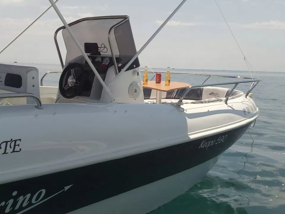 Vista lateral de una lancha motora blanca llamada Keppe 500 deslizándose por la Costa del Sol, con tres botellas de cerveza sobre una pequeña mesa, ideal para una relajante experiencia de Navega en Pareja por la Costa del Sol. - ForTwo - Planes para parejas