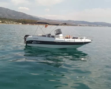 El Navega en Pareja por la Costa del Sol, un pequeño barco a motor blanco y azul, flota en las serenas aguas cerca de la hermosa costa de la Costa del Sol, con montañas distantes como un impresionante telón de fondo. - ForTwo - Planes para parejas