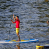 En el Embalse del Sichar, dos personas practican paddle surf, uno viste camiseta roja y pantalón corto amarillo, mientras que el otro viste ropa oscura. - ForTwo - Planes para parejas