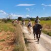 Las parejas pueden disfrutar de un romántico "Paseo a caballo en Llíria: un plan romántico en la naturaleza" por un camino de tierra a través de campos abiertos bajo un cielo azul con nubes dispersas. - ForTwo - Planes para parejas