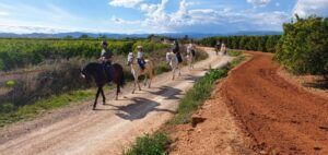 Los ciclistas disfrutan del Paseo a caballo en Llíria: un plan romántico en la naturaleza, explorando el pintoresco paisaje de Llíria a lo largo de un camino de tierra bajo un cielo soleado. - ForTwo - Planes para parejas
