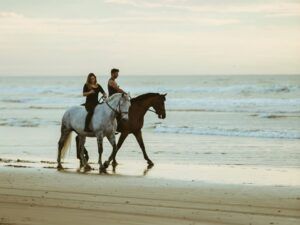 Dos personas disfrutan de un "Paseo a caballo por la playa de Xeraco", cabalgando por la tranquila playa al atardecer con relajantes olas de fondo. - ForTwo - Planes para parejas