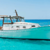 Un Paseo en Barco por la Costa de Palma está anclado en las cristalinas aguas turquesas, frente a un cielo azul brillante. - ForTwo - Planes para parejas
