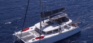 Vista aérea del Paseo en Yate por Tenerife, un catamarán blanco con equipamiento rojo, navegando elegantemente en las profundas aguas azules cerca de Tenerife. - ForTwo - Planes para parejas