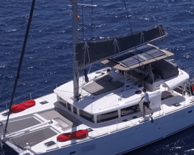 Vista aérea del Paseo en Yate por Tenerife, un catamarán blanco con equipamiento rojo, navegando elegantemente en las profundas aguas azules cerca de Tenerife. - ForTwo - Planes para parejas