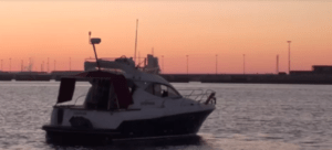 Un "Paseo en barco romántico por Bilbao" al atardecer revela un cielo rosa y naranja, resaltando la costa a lo lejos. - ForTwo - Planes para parejas