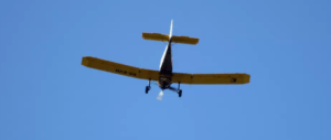 Un pequeño avión amarillo planea bajo un cielo azul claro, ofreciendo la experiencia "Piloto por un día en Atarfe" que captura la emoción de volar. - ForTwo - Planes para parejas