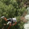 Un adicto a la adrenalina entra en acción con "Puenting en el río Genil", saltando en bungee sobre el hermoso río en medio de un dosel de árboles verdes para una aventura emocionante. - ForTwo - Planes para parejas