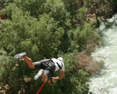 Un adicto a la adrenalina entra en acción con "Puenting en el río Genil", saltando en bungee sobre el hermoso río en medio de un dosel de árboles verdes para una aventura emocionante. - ForTwo - Planes para parejas