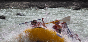 Dos personas en una balsa amarilla navegan expertamente por las agitadas aguas del Río Mijares usando sus remos durante una aventura de "Rafting en el Río Mijares". - ForTwo - Planes para parejas