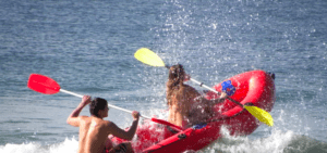 Dos aventureros practicando Rafting en el Río Mijares, navegando hábilmente entre las turbulentas olas mientras el agua salpica a su alrededor. - ForTwo - Planes para parejas