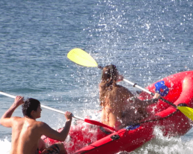 Dos aventureros practicando Rafting en el Río Mijares, navegando hábilmente entre las turbulentas olas mientras el agua salpica a su alrededor. - ForTwo - Planes para parejas