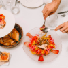Una persona presenta la ruta de tapas y vinos de Valencia, acompañada de una cesta de pan y salsas, creando una animada escena gastronómica en la mesa. - ForTwo - Planes para parejas