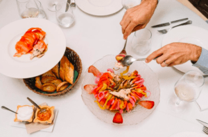 Una persona presenta la ruta de tapas y vinos de Valencia, acompañada de una cesta de pan y salsas, creando una animada escena gastronómica en la mesa. - ForTwo - Planes para parejas