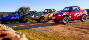Tres mini camionetas Ruta en 4x4 por Sierra Morena con diseños coloridos con temática de camuflaje están estacionadas en un camino de tierra, mostrando la belleza agreste del entorno escénico al aire libre de Sierra Morena. - ForTwo - Planes para parejas