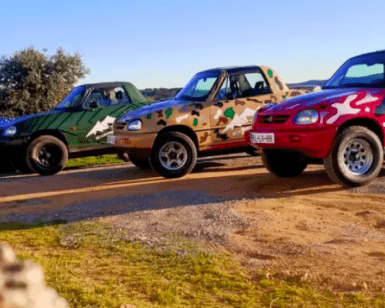 Tres mini camionetas Ruta en 4x4 por Sierra Morena con diseños coloridos con temática de camuflaje están estacionadas en un camino de tierra, mostrando la belleza agreste del entorno escénico al aire libre de Sierra Morena. - ForTwo - Planes para parejas