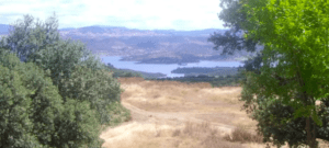 Disfrute de las vistas de un lago sereno, pastizales secos y colinas distantes bajo un cielo parcialmente nublado en la Ruta en 4x4 por Sierra Morena. - ForTwo - Planes para parejas
