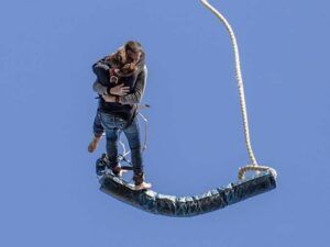 Dos personas se abrazan en el aire durante un emocionante Salto Bungee Tándem en Lloret de Mar, con el cielo azul claro como fondo. - ForTwo - Planes para parejas