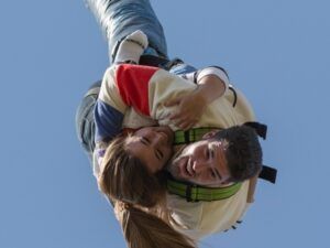 Dos personas practican puenting tándem en Lloret de Mar, sonriendo y abrazándose contra un cielo azul claro, disfrutando de la emoción de una aventura de Salto Bungee Tándem. - ForTwo - Planes para parejas