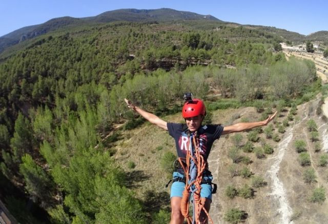 Una persona con casco rojo realiza puenting con los brazos extendidos sobre un paisaje boscoso, reflejando la emoción de "Salto de puenting en Valencia con vídeo: ¡vive la adrenalina en pareja!". - ForTwo - Planes para parejas