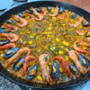 Una paella vibrante del Taller de Paella y Sangría en Valencia, rellena de camarones y mejillones, bellamente adornada con hierbas. - ForTwo - Planes para parejas