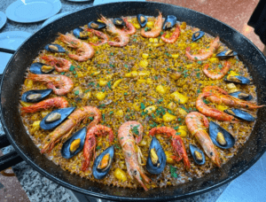 Una paella vibrante del Taller de Paella y Sangría en Valencia, rellena de camarones y mejillones, bellamente adornada con hierbas. - ForTwo - Planes para parejas