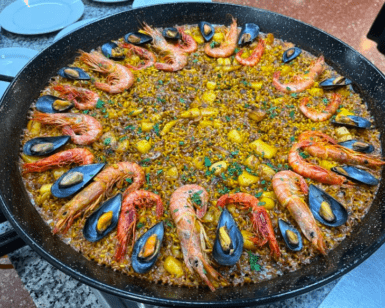 Una paella vibrante del Taller de Paella y Sangría en Valencia, rellena de camarones y mejillones, bellamente adornada con hierbas. - ForTwo - Planes para parejas