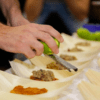 En el famoso Taller Mediterráneo de Sabores en Palma de Palma, una persona que ralla una lima realza diversos platos servidos en hojas de plátano, dando vida a sabores vibrantes. - ForTwo - Planes para parejas