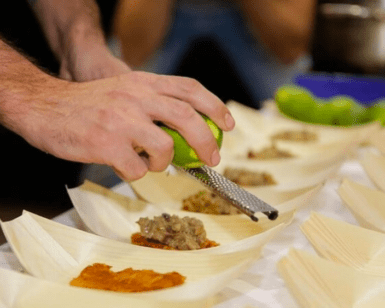 En el famoso Taller Mediterráneo de Sabores en Palma de Palma, una persona que ralla una lima realza diversos platos servidos en hojas de plátano, dando vida a sabores vibrantes. - ForTwo - Planes para parejas