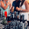 Una escena animada se desarrolla mientras la gente charla en un bar de Cala d’Or, con pajitas de cóctel en foco, evocando la esencia del Taller de coctelería en Cala d’Or. - ForTwo - Planes para parejas