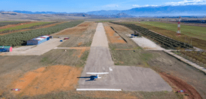 Una avioneta en una pista rural, ideal para un Vuelo en Avioneta por Granada, está rodeada de exuberantes campos y majestuosas montañas. - ForTwo - Planes para parejas