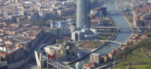 Vuelo sobre Bilbao y la costa de Bizkaia ofrece una impresionante vista aérea de la ciudad, que revela el icónico Museo Guggenheim, su imponente horizonte, el sinuoso río y los intrincados puentes que definen su paisaje urbano. Experimente Bilbao en toda su belleza arquitectónica y natural. - ForTwo - Planes para parejas