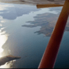 Una vista en avioneta muestra un río resplandeciente que serpentea a través de islas montañosas y boscosas bajo un cielo azul durante el Vuelo sobre el Pantano de Orellana. - ForTwo - Planes para parejas