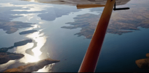 Una vista en avioneta muestra un río resplandeciente que serpentea a través de islas montañosas y boscosas bajo un cielo azul durante el Vuelo sobre el Pantano de Orellana. - ForTwo - Planes para parejas
