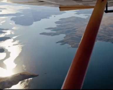 Una vista en avioneta muestra un río resplandeciente que serpentea a través de islas montañosas y boscosas bajo un cielo azul durante el Vuelo sobre el Pantano de Orellana. - ForTwo - Planes para parejas