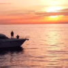 El Yate de lujo en Alcocéber navega por las serenas aguas, su forma resaltada contra una vívida puesta de sol y un cielo naranja. - ForTwo - Planes para parejas